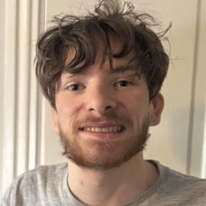 Luke, smiling, in a grey t-shirt